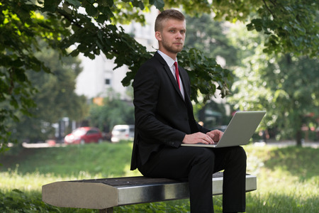 Happy Business Man Using Tablet Pc Outside On A Park Benchの写真素材