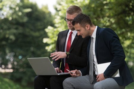 Happy Business Men Using Tablet Pc Outside On A Park Benchの写真素材