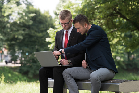 Happy Business Men Using Tablet Pc Outside On A Park Benchの写真素材