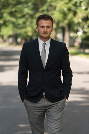 Young Businessman Walking Outdoors In Park While Resting From Office Workの写真素材