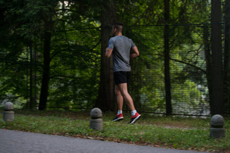 Young Man Running In Wooded Forest Area - Training And Exercising For Trail Run Marathon Endurance -...