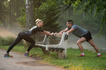 Young Couple Stretching Before Running In Wooded Forest Area - Training And Exercising For Trail Run Marathon Endurance - Fitness Healthy Lifestyle Conceptの写真素材