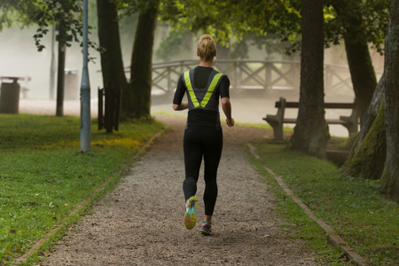 Young Woman Running In Wooded Forest Area - Training And Exercising For Trail Run Marathon Endurance - Fitness Healthy Lifestyle Conceptの写真素材