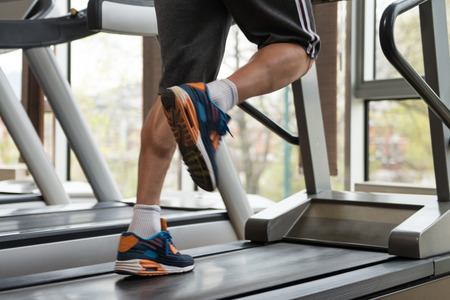 Close Up Of Male Legs Running On Treadmill - Blurred Motionの写真素材