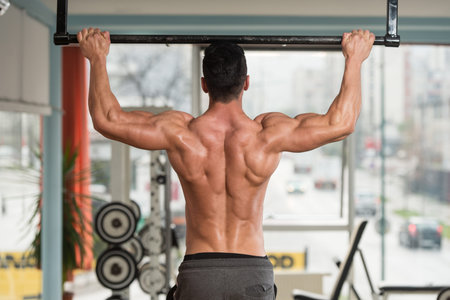 Young Male Athlete Doing Pull Ups - Chin-Ups In The Gym