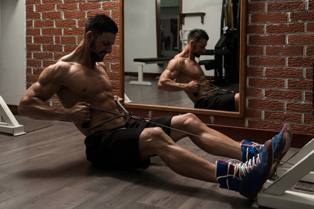 Bodybuilder Doing Heavy Weight Exercise For Back On Machineの写真素材