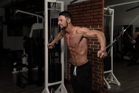 Bodybuilder Is Working On His Chest With Cable Crossover In A Dark Gymの写真素材
