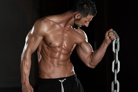 Healthy Bodybuilder Exercising Biceps With Chainsの写真素材