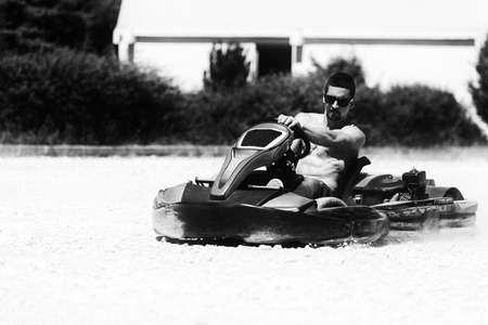 Young Man Is Driving Go-Kart Car With Speed In A Playground Racing Track - Go Kart Is A Popular Leisure Motor Sportsの写真素材