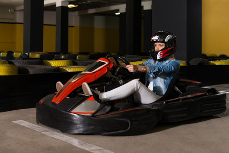 Young Woman Is Driving Go-Kart Car With Speed In A Playground Racing Track - Go Kart Is A Popular Leisure Motor Sportsの写真素材