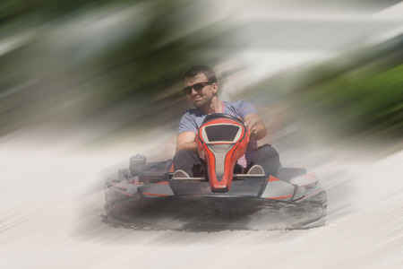 Young Man Is Driving Go-Kart Car With Speed In A Playground Racing Track - Go Kart Is A Popular Leisure Motor Sportsの写真素材
