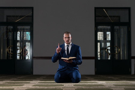 Muslim Businessman Reading Holy Islamic Book Koran In The Mosqueの写真素材