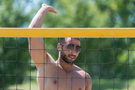 Muscular Young Man Playing Beach Volleyball Diving After The Ballの写真素材