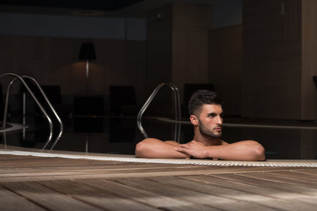 Happy Attractive Man Resting Relaxed On Edge Of Swimming Pool