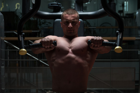 Bodybuilder Doing Heavy Weight Exercise For Chest On Machineの写真素材