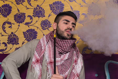 Muslim Man Smoking Turkish Hookah In The Cafe With Colorful Walls On Backgroundの写真素材
