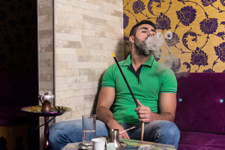 Man Smoking Turkish Hookah In The Cafe With Colorful Walls On Backgroundの写真素材