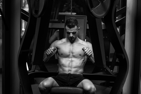 Handsome Man Is Working Out Chest On Machine In A Modern Gymの写真素材
