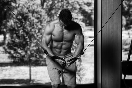 Muscular Young Man Bodybuilder Doing Heavy Weight Exercise For Chest On Cable Machineの写真素材