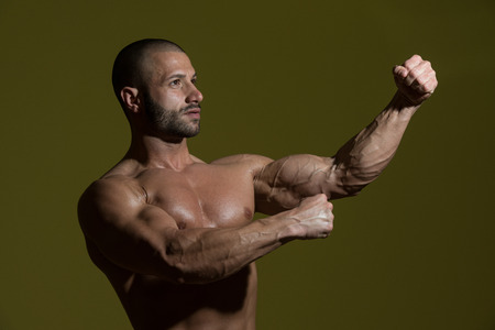 Portrait Of A Physically Fit Man Showing His Well Trained Body In Dark Roomの写真素材