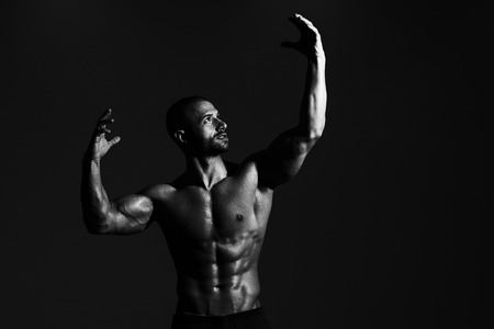 Portrait Of A Physically Fit Man Showing His Well Trained Body In Dark Roomの写真素材