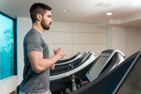 Handsome Man Running On The Treadmill In Gymの写真素材