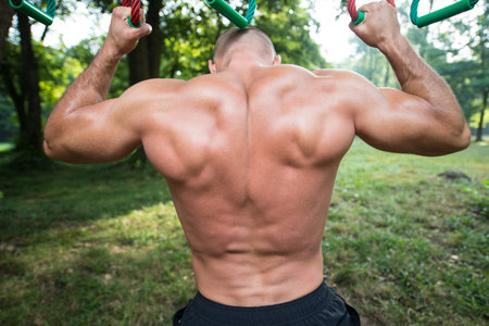Close-Up Muscular Built Young Athlete Working Out In An Outdoor Gym - Doing Chin-Ups