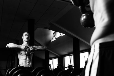 Young Man Working With Kettle Bell In Front Of A Mirror
