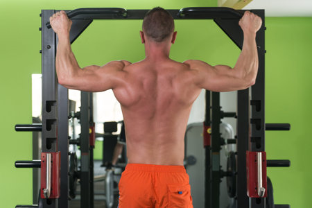 Young Man Athlete Doing Pull Ups - Chin-Ups In The Gym