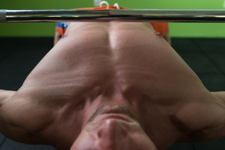 Close-Up Of A Young Man In Gym Exercising Chest On The Bench Press