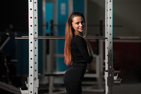 Beautiful Young Woman With Long Hair In A Black Skirt Posing In Gym - Squat Cageの写真素材