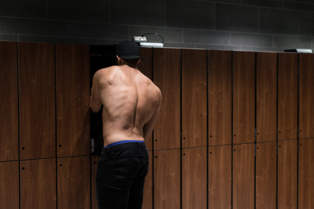 Young Fit Adult Man Changing Clothings In Locker Room Of Gym Facilityの写真素材