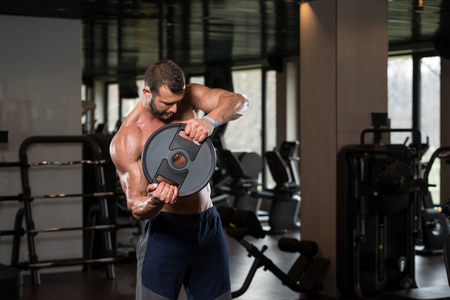 Young Man Exercising Abs With Weights In A Modern Fitness Gymの写真素材
