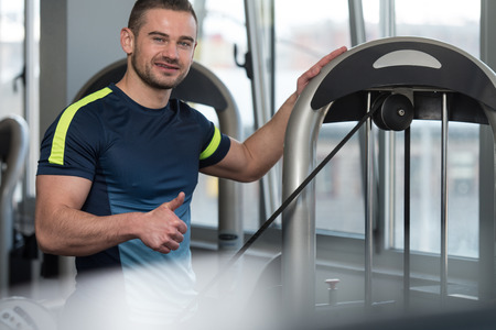 Personal Trainer Showing Ok Sign To Client - Group Of People Exercising On Elliptical Walker In Gym Or Fitness Clubの写真素材