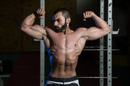 Portrait Of A Young Fit Man Performing Front Double Biceps Pose - Muscular Athletic Bodybuilder Fitness Model Posing After Exercisesの写真素材