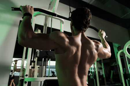 Young Bodybuilder Doing Heavy Weight Exercise For Back On Machine