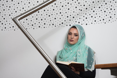 Beautiful Muslim Woman Wearing Hijab And Reading The Koranの写真素材