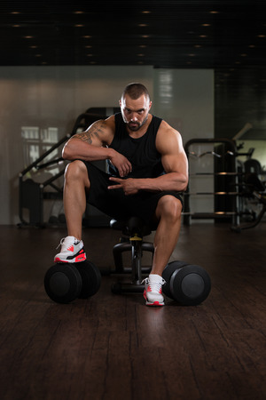 Portrait Of A Muscular Man Resting On The Bench In Fitness Gymの写真素材