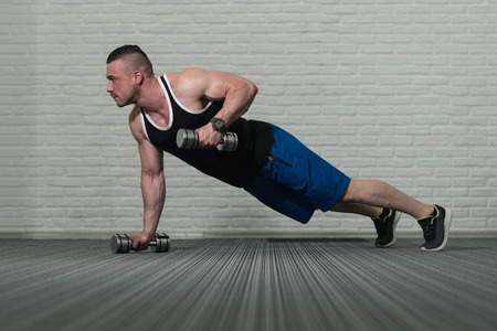 Young Bodybuilder Doing Pushups With Dumbbells As Part Of Bodybuilding Trainingの写真素材