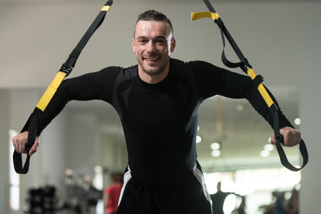 Attractive Man Does Crossfit With Trx Fitness Straps In The Gym's Studio