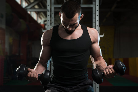 Young Man Working Out Biceps In A Dark Gym - Dumbbell Concentration Curls