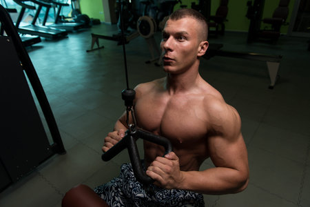 Muscular Athletic Bodybuilder Fitness Model Doing Heavy Weight Exercise For Back On Machine