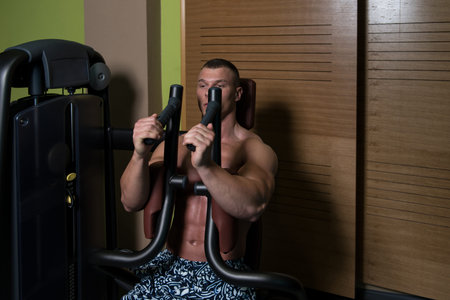 Muscular Athletic Bodybuilder Fitness Model Doing Heavy Weight Exercise For Chest On Machine