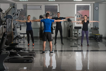 Instructor With Fitness Class Performing Step Aerobics Exercise In Gym