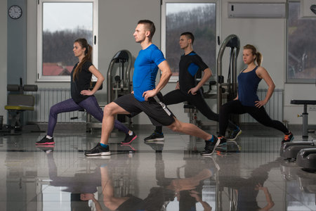 Group Of Young People Stretching In Gym For Better Fitness Led By Instructor