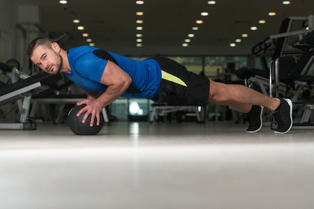 Personal Trainer Doing Pushups With Medicine Ball As Part Of Bodybuilding Trainingの写真素材