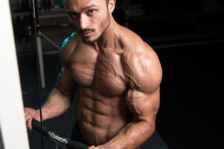 Handsome Muscular Fitness Bodybuilder Doing Heavy Weight Exercise For Biceps On Machine With Cable...