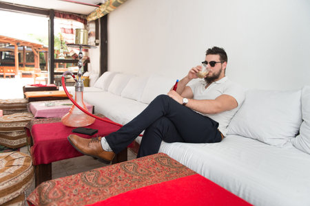 Man Smoking Turkish Hookah In The Cafe With Colorful Walls On Background