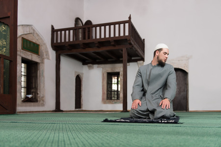 Young Muslim Man Making Traditional Prayer To God While Wearing A Traditional Cap Dishdashaの写真素材