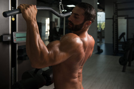 Latin Bodybuilder Doing Heavy Weight Exercise For Back On Machine